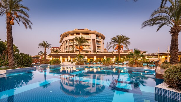 Un hotel grande y circular con una piscina en primer plano.