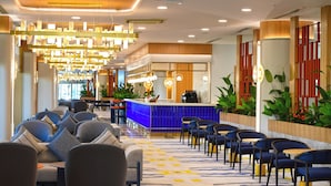 Un hall de hotel con mostrador de recepción, zona de estar e iluminación decorativa.