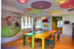 Una habitación de colores vivos con una mesa grande y sillas, un mural en la pared y un letrero que dice 