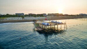 Un muelle con una plataforma de observación y sillas de descanso que se adentra en una masa de agua tranquila.