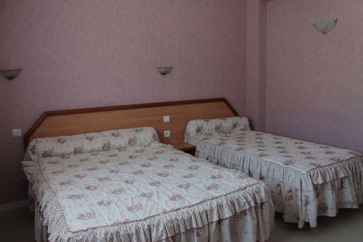 A room with two single beds, each with floral-patterned bedding and a wooden headboard.