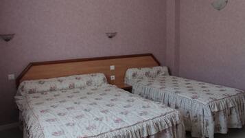 Una habitación con dos camas individuales, cada una con ropa de cama estampada con motivos florales y cabeceros de madera.