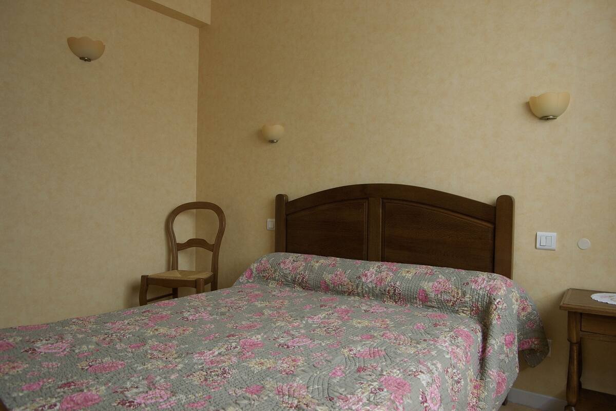 A bedroom with a wooden bed, a chair, and two wall-mounted light fixtures.
