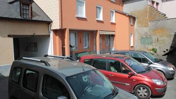 A parking lot with several cars parked in front of a building with a sloped roof and multiple windows.