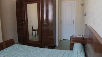 Een slaapkamer met een bed, een kledingkast, een stoel en een deur.