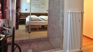 A room with a bed, a radiator, a mirror, and a wall with a quote. - Garnì Ladin (San Giovanni di Fassa)