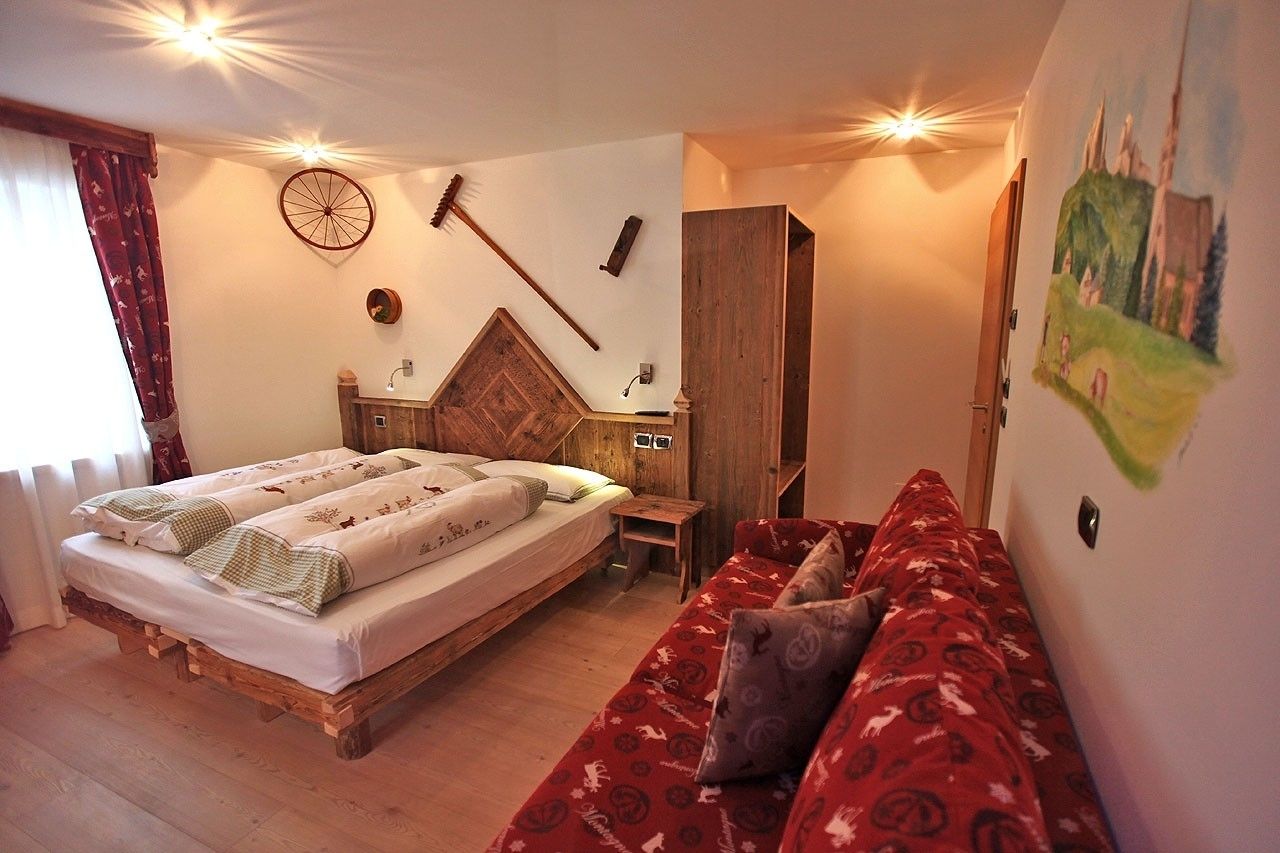 Ein gemütliches Zimmer mit einem hölzernen Bett, einem roten Sofa und einem Holzschrank.