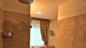A bathroom with a shower, a wooden chair, and a radiator. - Garnì Ladin (San Giovanni di Fassa)
