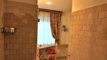 Ein Badezimmer mit Dusche, einem Holzstuhl und einem Heizkörper.