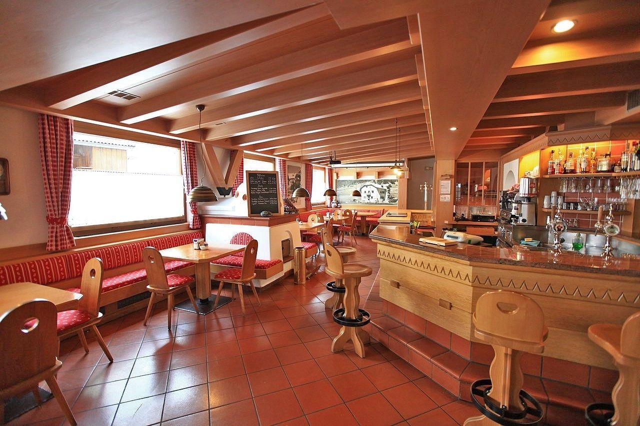 Un restaurant doté de mobilier en bois, d’un bar et offrant une vue sur l’extérieur.