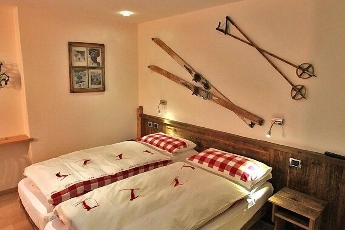 Un dormitorio con una cama de madera, una mesita de noche pequeña y esquíes colgados en la pared.
