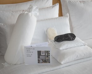 A neatly made bed with white linens, a black eye mask, and a brochure. - AMERON Hamburg Hotel Speicherstadt (Hamburg)