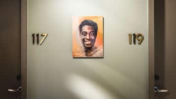Un couloir avec des portes numérotées 117 et 119, orné d’un portrait encadré accroché au mur.