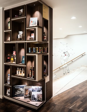 A wooden display shelf with various items including books, bottles, and a framed picture. - AMERON Hamburg Hotel Speicherstadt (Hamburg)