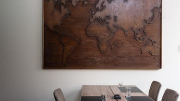 Un mapa mural del mundo de madera sobre una pared, sobre una mesa de comedor de madera con sillas.