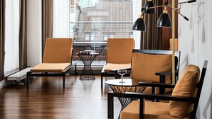 A modern hotel room with a large window offering a view of a historic building. There are two lounge chairs and a small table with a glass top. - AMERON Hamburg Hotel Speicherstadt (Hamburg)