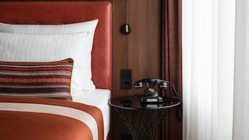 A hotel room with a bed, a desk with a telephone, and a lamp.
