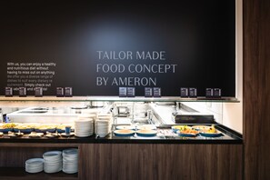 A buffet counter with various dishes and a menu board displaying the text "TAILOR MADE FOOD CONCEPT BY AMERON". - AMERON Hamburg Hotel Speicherstadt (Hamburg)