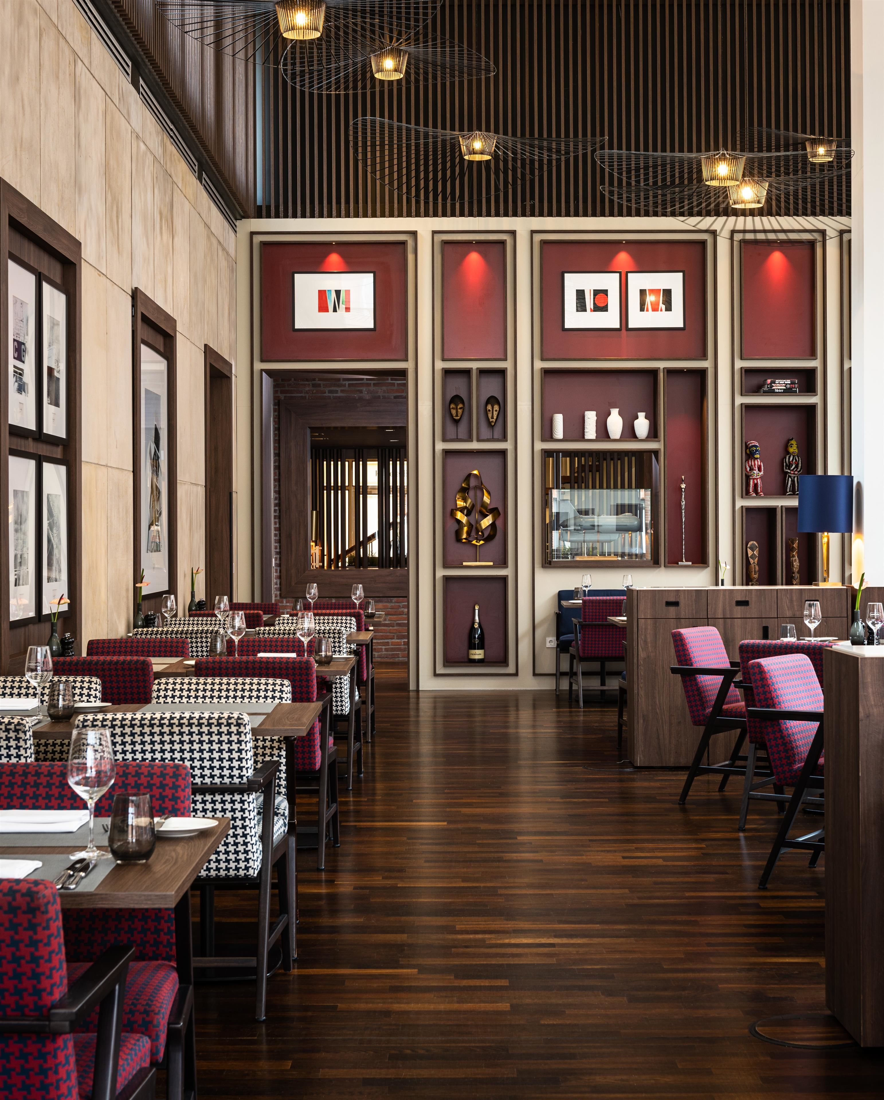 Un restaurant avec des planchers en bois, des chaises à motifs pied-de-poule et une décoration rouge et blanche.