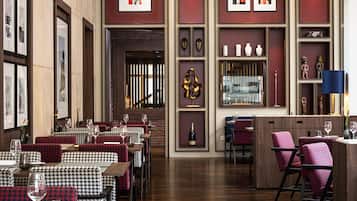 A restaurant with wooden floors, houndstooth-patterned chairs, and red and white decor.