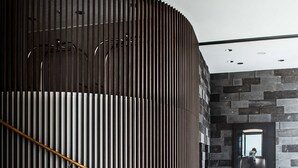 A modern staircase with a wooden handrail, flanked by dark vertical panels and a stone wall with a framed picture. - AMERON Hamburg Hotel Speicherstadt (Hamburg)