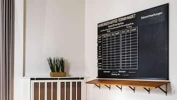A modern meeting room with a large blackboard displaying a menu, a wooden table, blue chairs, and a potted plant.