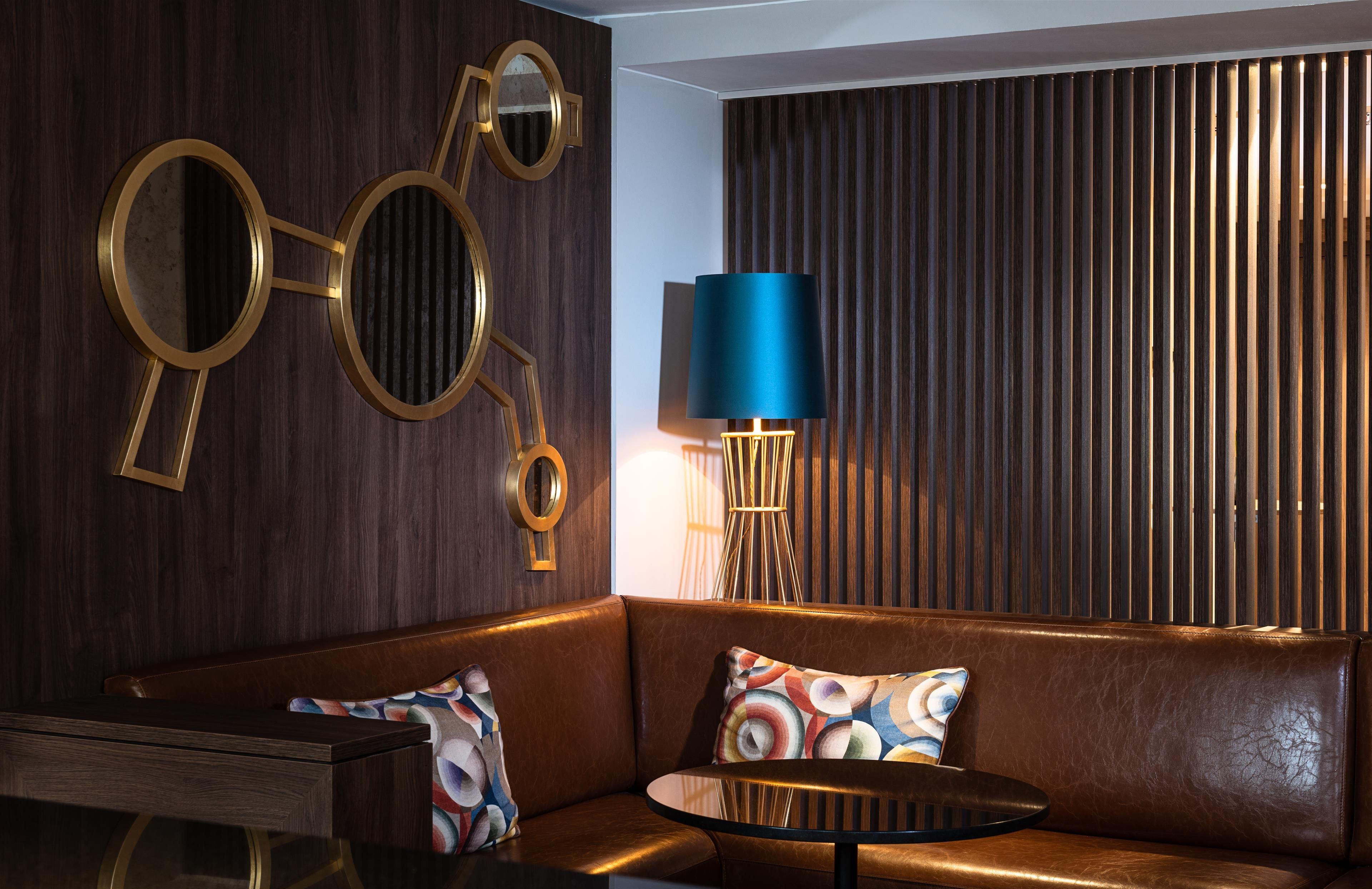 Un salon moderne avec un canapé en cuir, une table basse ronde et une lampe bleue.