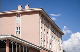 Un edificio rosa con techo plano y ventanas arqueadas.