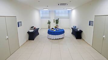 A conference room with a central table, two side tables, and potted plants.