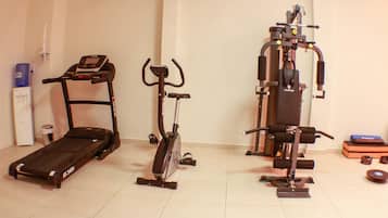 Uma academia em casa com esteira, bicicleta ergométrica e aparelho de musculação.