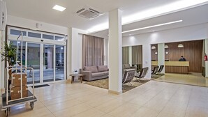 A spacious lobby with a reception desk, seating area, and a luggage cart. - The Hill Executive (São Carlos)