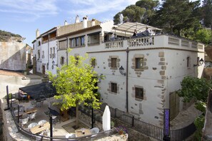 A building with a balcony, outdoor seating, and a tree. - Casa Granados Boutique Hotel (Tossa de Mar)