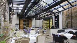 An indoor dining area with tables set for a meal, surrounded by chairs, and a glass ceiling above. - Casa Granados Boutique Hotel (Tossa de Mar)