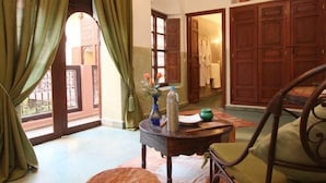A room with a wooden chair, a small table with a vase and a bottle, and a view of a courtyard through an open door. - Riad Sidi Ayoub (Marrakech)