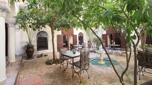 A courtyard with a table and chairs, a fountain, and potted plants. - Riad Sidi Ayoub (Marrakech)
