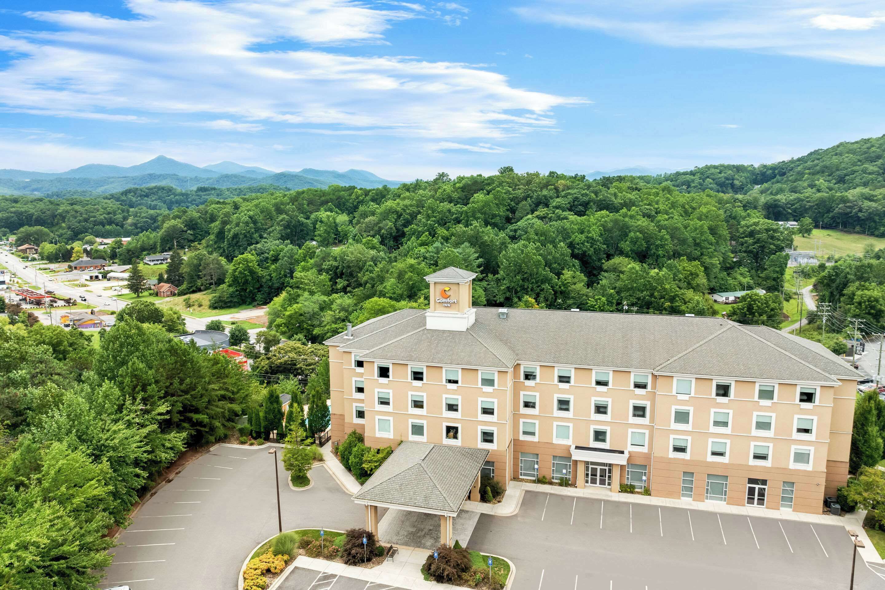 A multi-story hotel with a central courtyard, surrounded by lush greenery and mountains in the background.