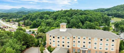 A multi-story hotel with a central courtyard, surrounded by lush greenery and mountains in the background.