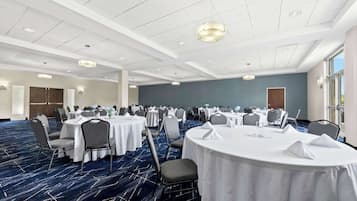 Une salle de conférence avec des tables rondes, des chaises et un tapis bleu.
