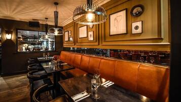 A restaurant interior with wooden tables, leather booths, and framed artwork on the walls.