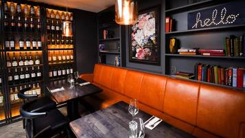 Un restaurante con una estantería de vinos, un letrero de neón que dice 'hello' y estanterías llenas de libros.