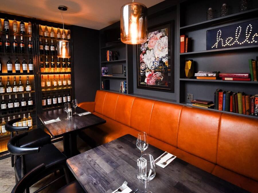 Un restaurant doté d'un bar à vin, d'un panneau néon affichant le mot « bonjour » et de bibliothèques.
