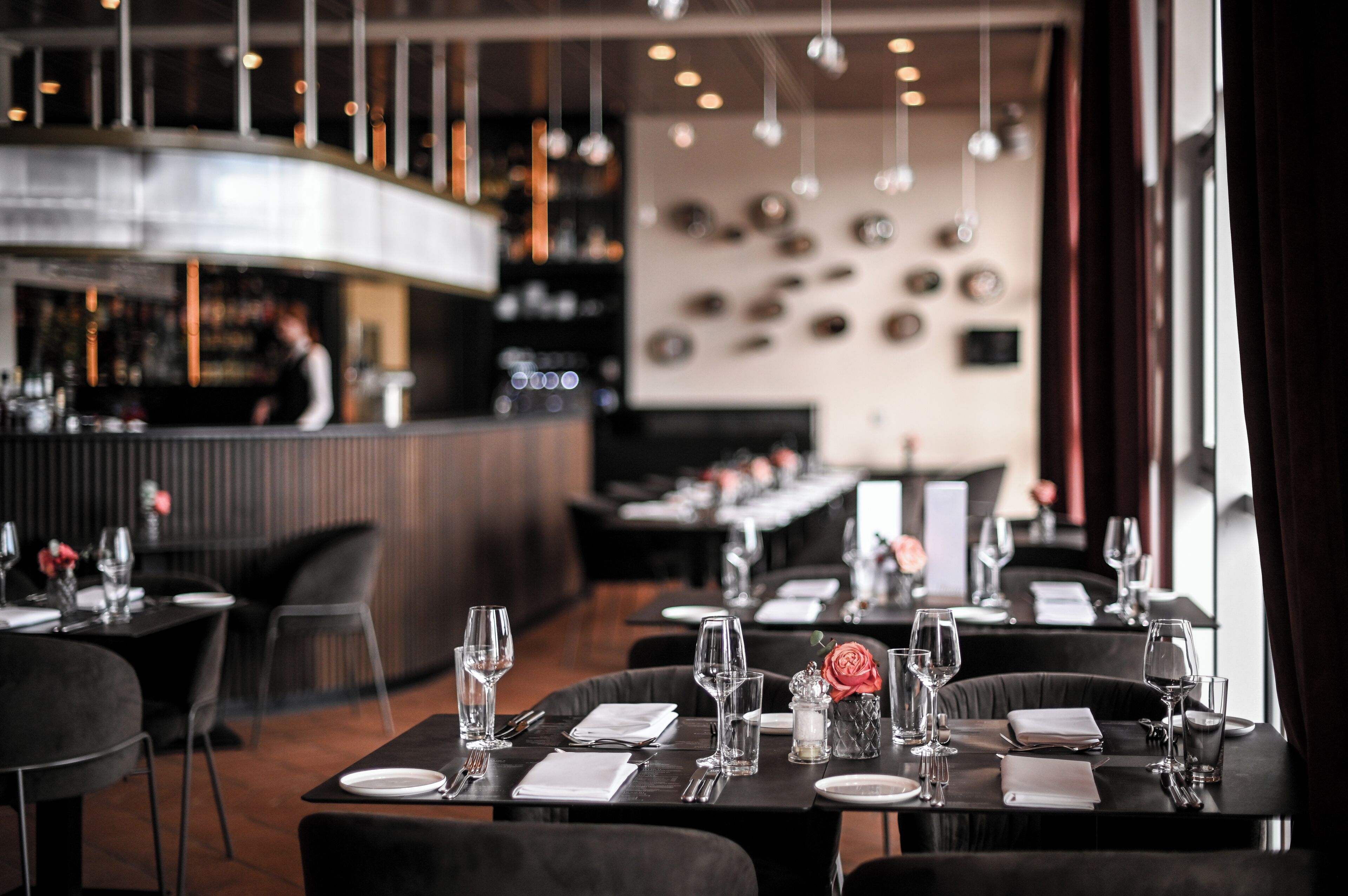 A restaurant with tables set for dining, a bar area, and a modern interior design.