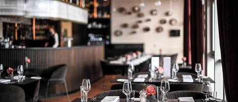 A restaurant with tables set for dining, a bar area, and a modern interior design.