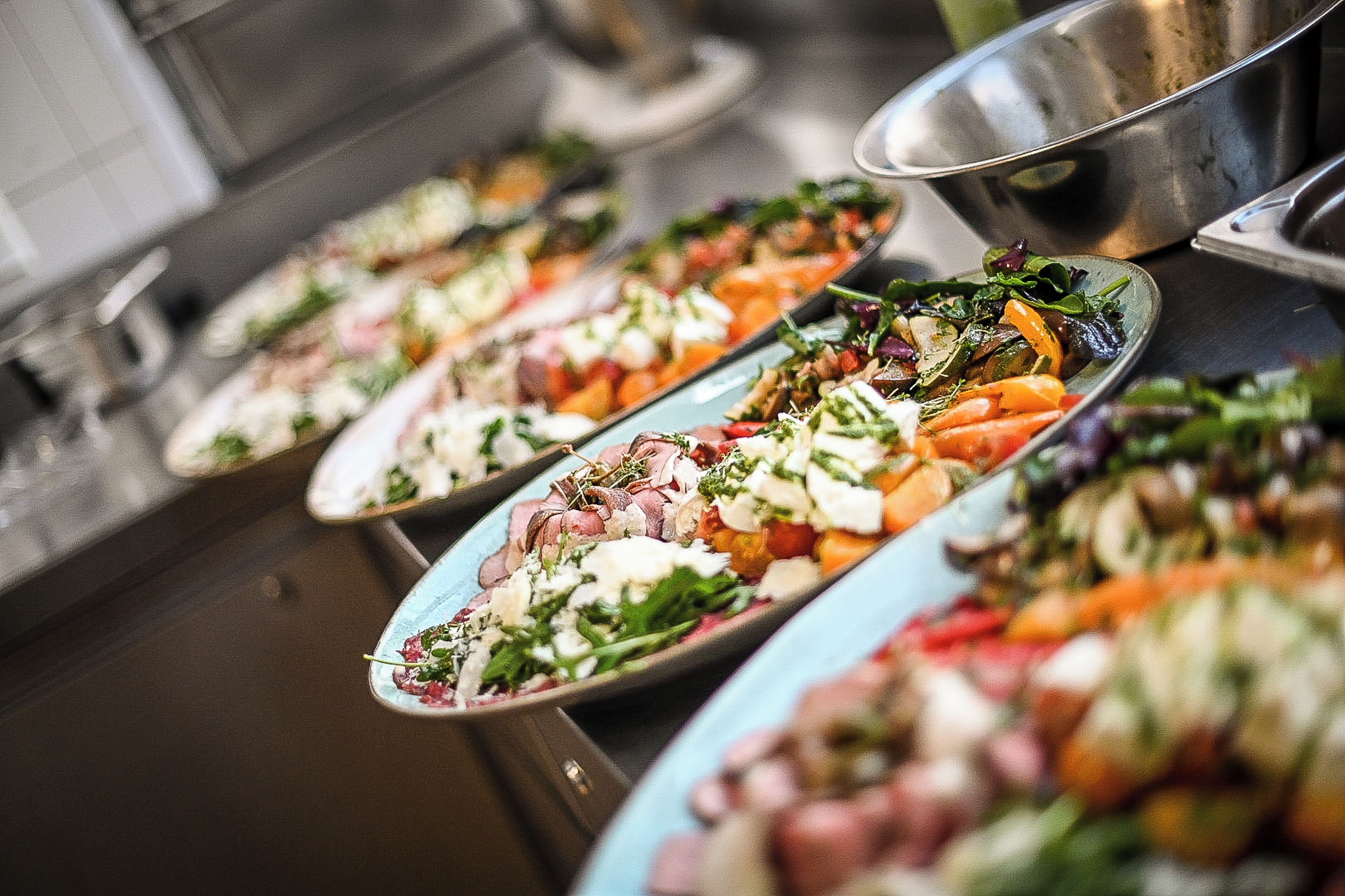 Un buffet proposant une variété de plats, notamment des salades, des viandes et des légumes.