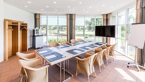 A conference room with a long table, chairs, a TV, and a whiteboard. - Golfhotel & Restaurant Lindenhof (Bad Vilbel)