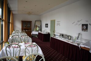 A dining room with tables set for a meal, a mirror, and a sewing machine on a table. - Hotel Antares (Halberstadt)