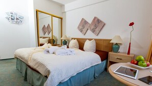 A hotel room with a neatly made bed, a bedside table with a lamp, a mirror, and a wall with photos and artwork. - Hotel Antares (Halberstadt)