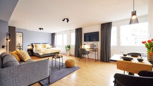 Een moderne hotelkamer met een bank, een bed, een eethoek en een televisie.