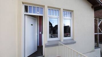 Un edificio con fachada blanca, una puerta y dos ventanas con un pequeño alero.
