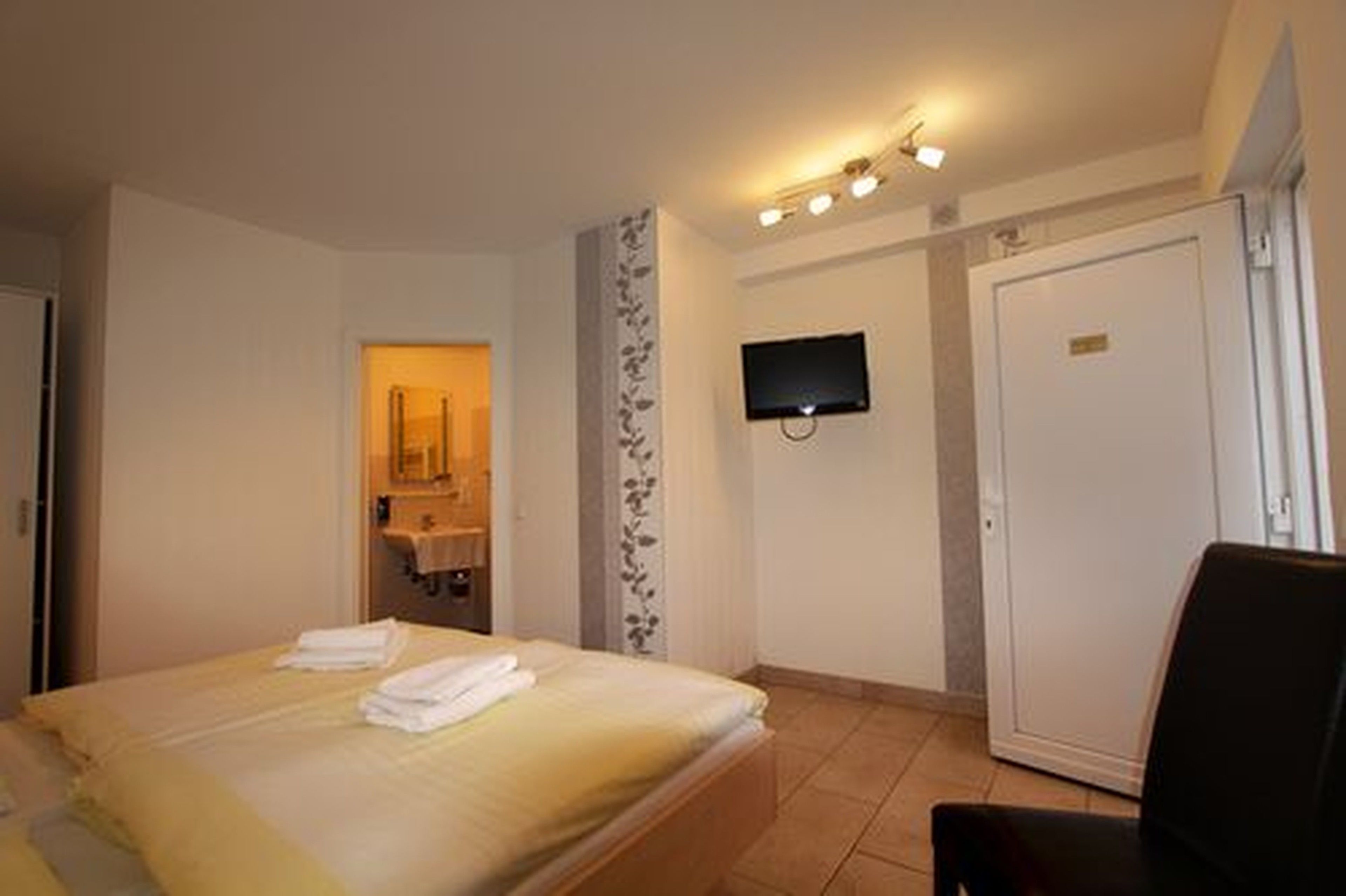 Une chambre d’hôtel avec un lit, un téléviseur fixé au mur et une porte.